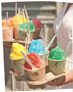 there are many different colored ice creams in cups on the tray and one is being held by a woman