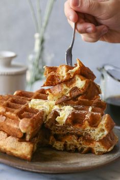 a person is cutting into some waffles on a plate