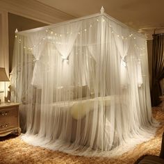 a canopy bed with white sheer curtains and lights