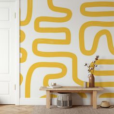 a yellow and white wallpaper in a room with a wooden table, vases and hat