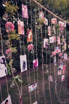 many pictures are hung on a string with flowers and photos hanging from it's sides