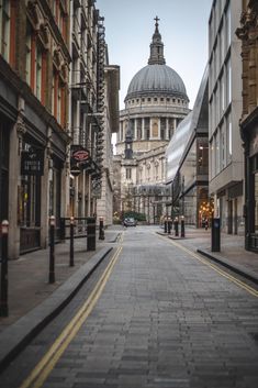 an empty city street with buildings on both sides and a domed building in the background