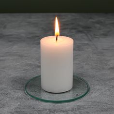 a lit candle sitting on top of a glass plate