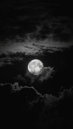 the full moon is seen through clouds in black and white