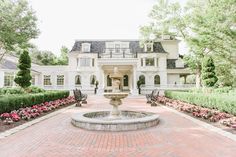 a large white house with a fountain in the front yard