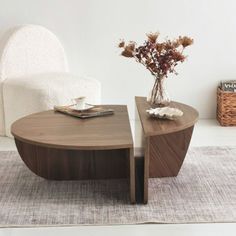 a coffee table sitting on top of a rug next to a chair and vase with flowers