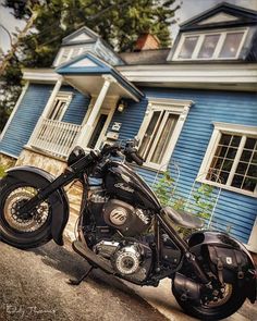 a black motorcycle parked in front of a blue house