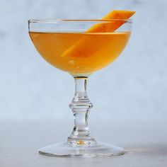 a glass filled with orange juice and garnished with an orange peel on the rim