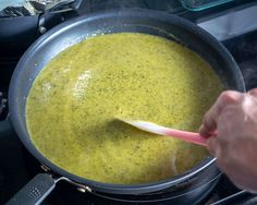 a person stirring a pot of soup on the stove