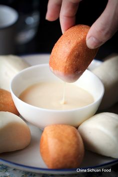 a person dipping some kind of food into a small white bowl on a blue and white plate