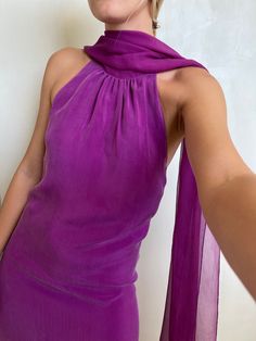 a woman in a purple dress poses for the camera with her hand on her hip