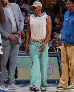 a man standing on top of a basketball court next to another man wearing green pants