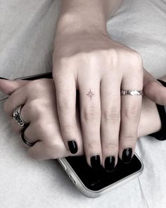 two people with black fingernails and rings on their fingers, one holding the other's hand