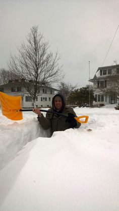 a woman is sitting in the snow holding a yellow flag and looking at the camera