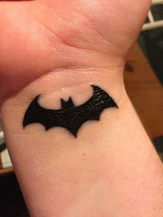 a small black bat tattoo on the wrist