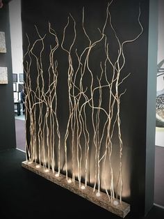 an art piece is displayed in front of a black wall with white branches on it