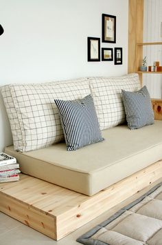 a couch with pillows on top of it in a living room next to a book shelf