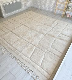 a white rug with fringes on the floor in front of a brick wall and radiator