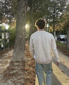 a man walking down a sidewalk next to a tree