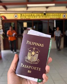 a person holding up a passport in front of a building