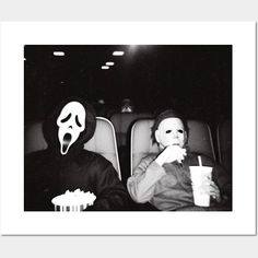 two people wearing masks sitting in the back of a car eating popcorn and drinking soda