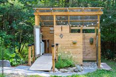 a small wooden structure in the middle of some grass and trees with a walkway leading up to it