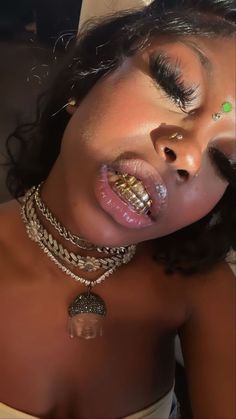 a close up of a woman with jewelry on her face and nose, wearing gold necklaces