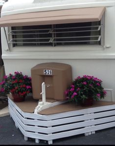 a white trailer with flowers on the side and a brown awning over it's window