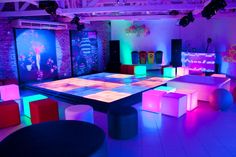 a room filled with lots of different colored lights and tables covered in colorful cloths