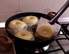 donuts being cooked in a frying pan on top of the stove with water