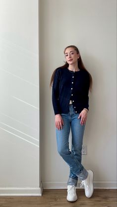 Classic chic outfit styling white sneakers. Navy blue cardigan, straight leg jeans, white belt, white sneakers, and jewelry. Appropriate for school/college or casual settings.