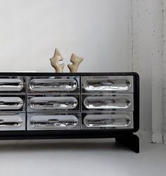 a black and chrome dresser with two vases on top