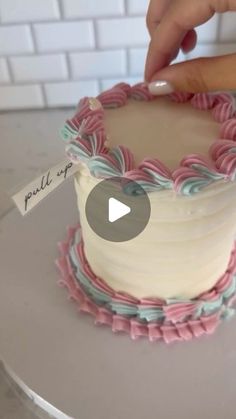 someone is decorating a cake with pink and blue icing on the top layer