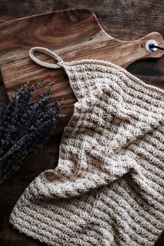 a knitted dishcloth next to a wooden cutting board with dried lavender on it