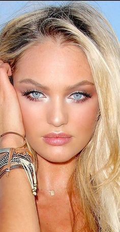 a beautiful blond woman with blue eyes and bracelets on her arm posing for the camera