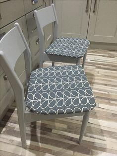 two chairs sitting on top of a kitchen floor next to a counter with cabinets in the background