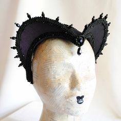 This is a purple and black version of one of most successful designs called Countess. This vampire style headdress is covered with dark purple taffeta and embellished with black cord trimming all around the edges.It is further trimmed with black crystal details that create a halo effect as well as small l beads that were hand-sewn on the trimming to create rich textural interest. The piece is completed with a black crystal handmade element placed at the center front for all that extra drama that Gothic Costume Hats And Headpieces For Masquerade Carnival, Gothic Costume Hats For Masquerade And Carnival, Gothic Adjustable Costume Accessories For Carnival, Adjustable Gothic Costume Accessories For Carnival, Black Fitted Fantasy Costume Hats And Headpieces, Gothic Costume Hats For Carnival And Cosplay, Gothic Costume Accessories For Carnival, Gothic Costume Accessories For Theater And Carnival, Fitted Costume Hat With Tall Crown