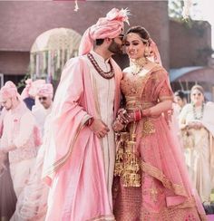 two people standing next to each other in front of a group of people wearing pink outfits