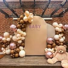 a teddy bear sitting on top of a wooden bench next to balloons in the shape of animals