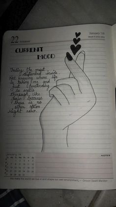 an open notebook with writing on it and a hand holding a heart in the middle