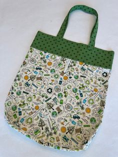 "An eco-friendly alternative to plastic bags, this tote folds up and fastens with elastic to slip in your purse, backpack or glove box and have at the ready.  Perfect for shopping, grocery store or farmers market.   Created from 2 coordinating fabrics with a green dot on the handles and top of the bag, and a cream print with eco-friendly motifs on the body of the bag.  The bag measures 18.5\" tall and 15.5\" wide, with 21\" handles to sit comfortably on your shoulder. Durable to be used again and again,  these bags are made from high quality quilting cotton fabric, with double stitched french seams on the sides and squared corners at the bottom.  Machine wash on cool or cold and hang or tumble dry when needed. No charge for shipping.   Thanks so much for visiting my shop.  See other sustai Cloth Tote Bag, Skull Fabric, Halloween Candy Bags, Tote Outfit, Painted Tote, Cloth Cocktail Napkins, Purse Backpack, Gardening Outfit, Travel Tote Bag