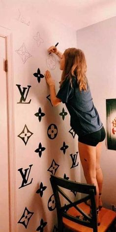 a woman standing on top of a chair in front of a wall with louis vuitton decals