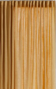 an orange curtain hanging from the side of a window with yellow curtains on top of it