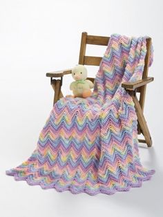 a crocheted blanket sitting on top of a wooden chair next to a teddy bear