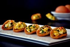 small appetizers are arranged on a white platter with oranges in the background