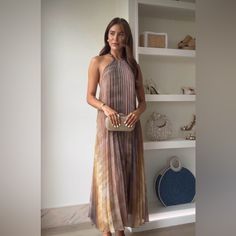 a woman standing in front of a book shelf holding a purse and posing for the camera