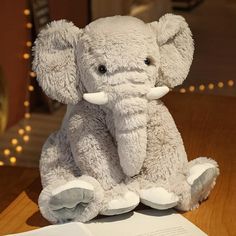 an elephant stuffed animal sitting on top of a table next to a piece of paper