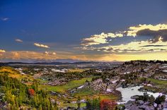 the sun is setting over some rocks and trees in the distance, with mountains in the background