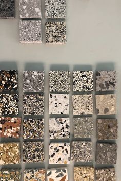 several different types of tiles arranged in rows on a white wall with grey and black speckles