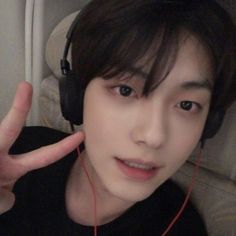 a young man wearing headphones and making the peace sign with his hand in front of him